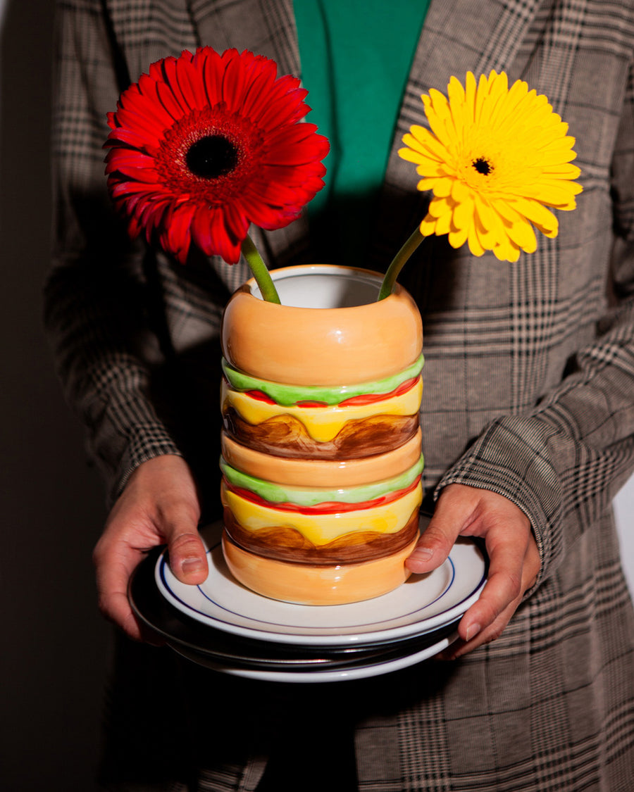 model holding cheeseburger shaped vase on a tray