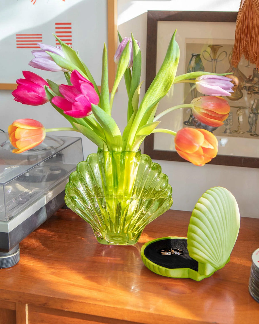 lime green glass seashell vase with tulips inside on a table