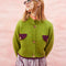 model wearing slightly cropped pea green cardigan with plum patch pockets and trim