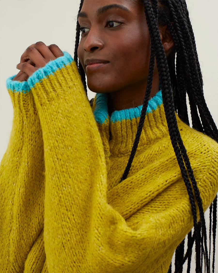 side view of model wearing oversized cardigan with light blue trim and four patch pockets on the front