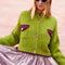 model wearing slightly cropped pea green cardigan with plum patch pockets and trim