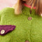 up close of model wearing slightly cropped pea green cardigan with plum patch pockets and trim