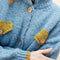 up close of model wearing slightly cropped light blue cardigan with olive green patch pockets and trim