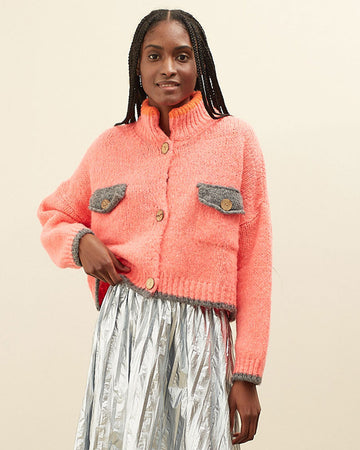 model wearing slightly cropped coral cardigan with grey patch pockets and trim