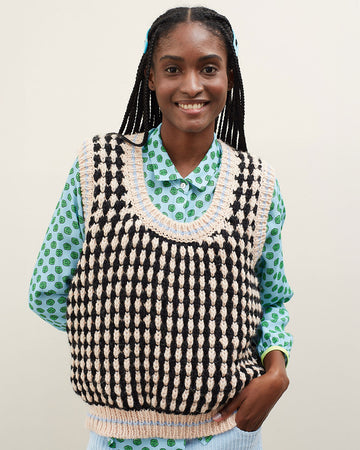 model wearing black and white textured sweater vest with slight blouson bottom