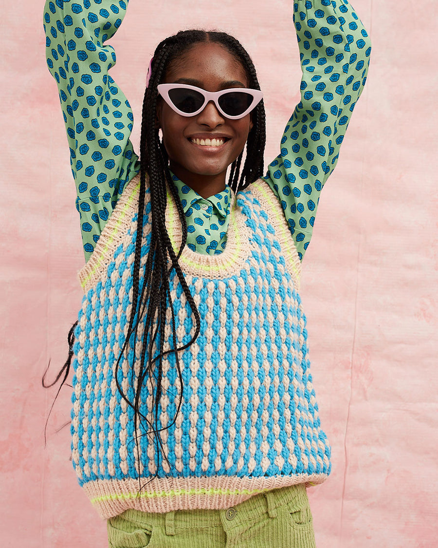 model wearing pink and blue textured sweater vest with slight blouson bottom