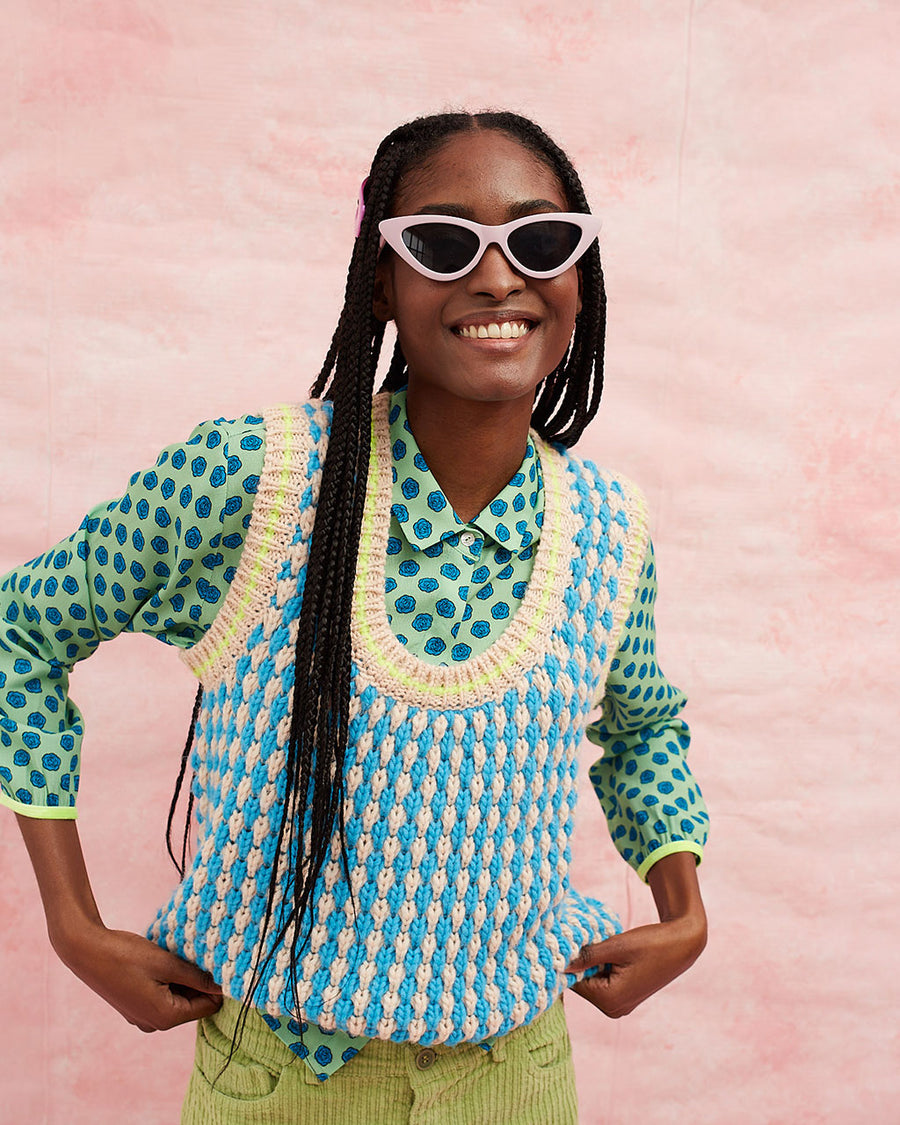 model wearing pink and blue textured sweater vest with slight blouson bottom