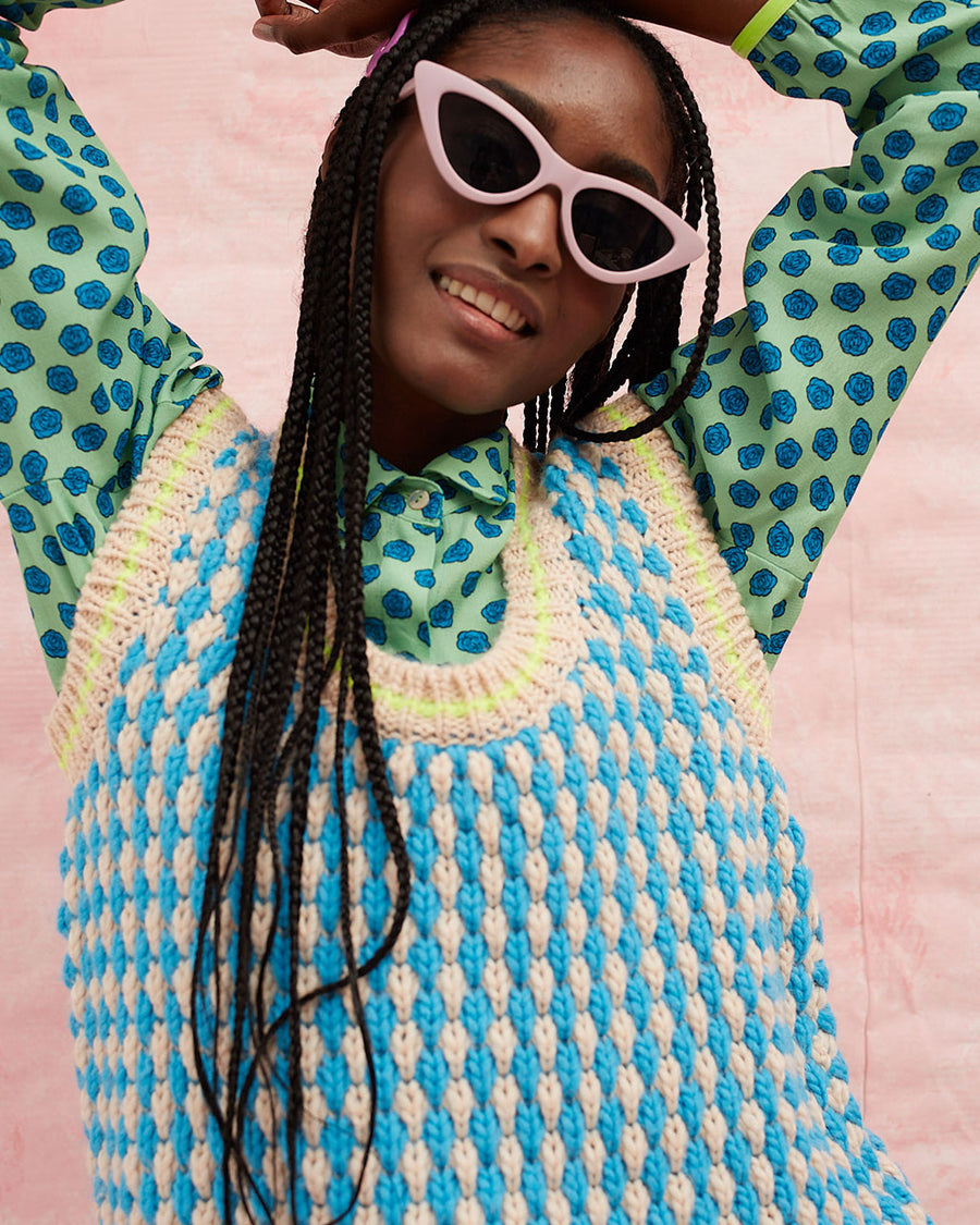 up close of model wearing pink and blue textured sweater vest with slight blouson bottom