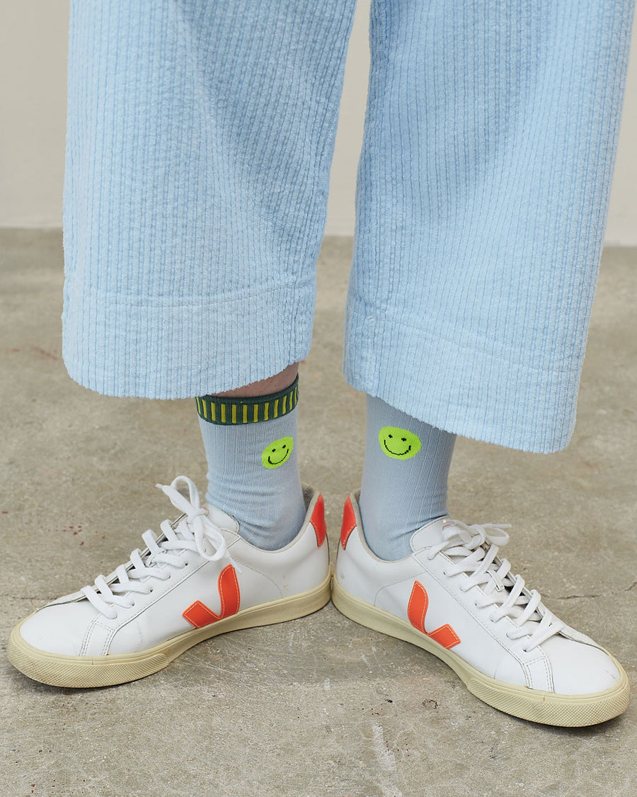 model wearing blue socks with neon smiley on the cuff