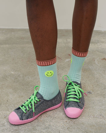 model wearing blue socks with neon smiley on the cuff