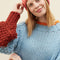 up close of model wearing light blue sweater with maroon cuffs and orange neckline