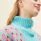 up close of model wearing blue sweater with button funnel neckline and pink abstract floral print