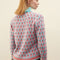 back view of model wearing blue sweater with button funnel neckline and pink abstract floral print