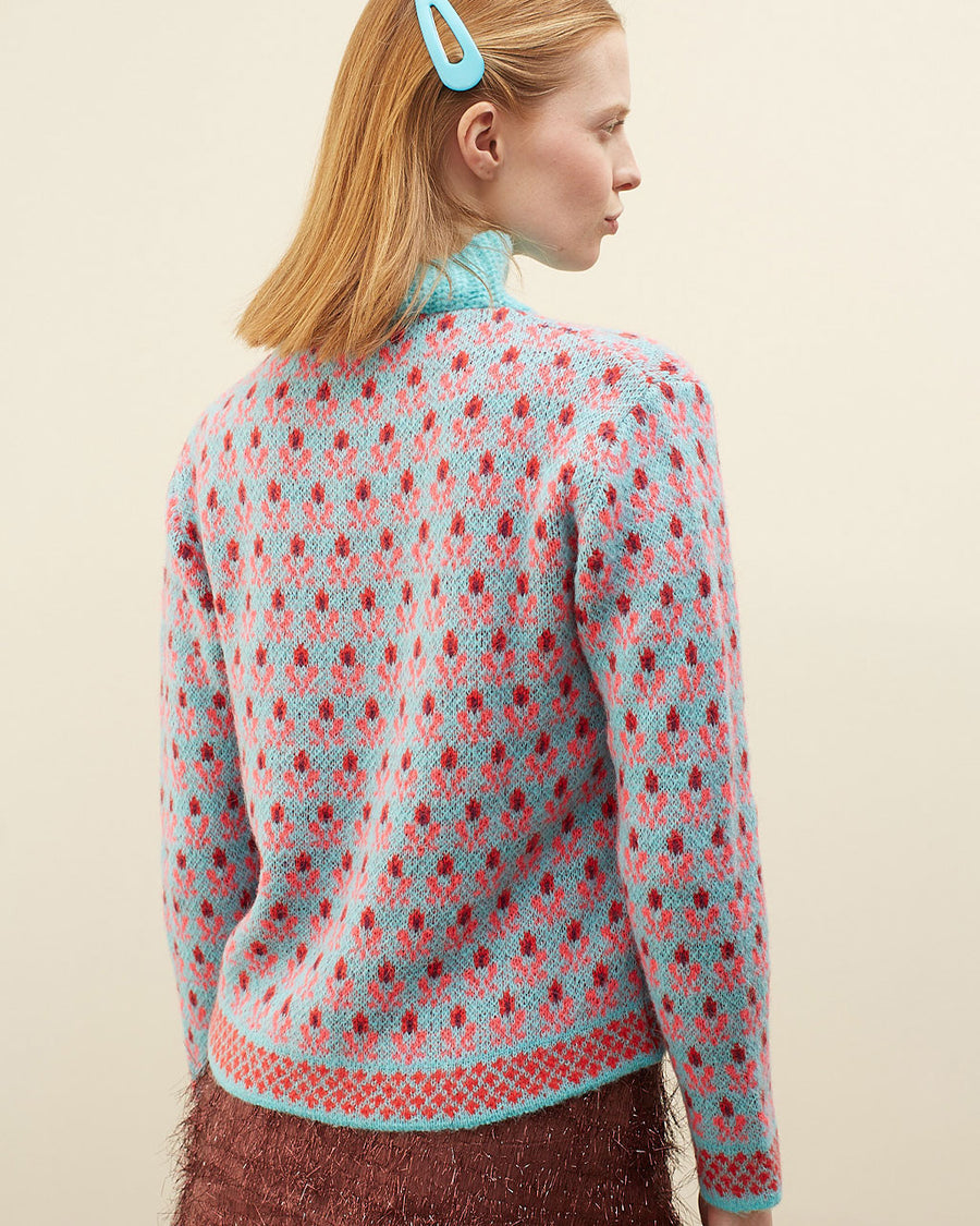 back view of model wearing blue sweater with button funnel neckline and pink abstract floral print