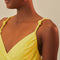 up close of model wearing yellow dress with criss cross bodice and knots in the straps