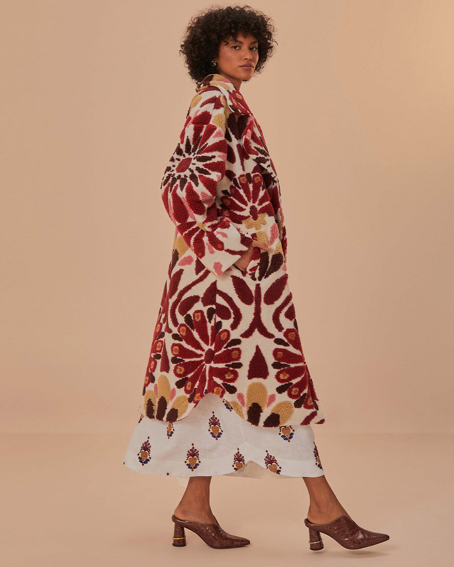 side view of model wearing fleece midi length coat with red and gold abstract floral print
