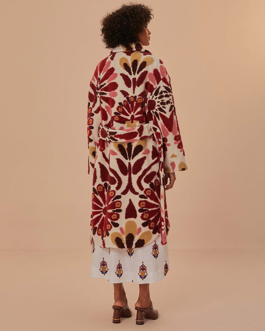 back view of model wearing fleece midi length coat with red and gold abstract floral print