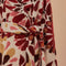 up close of tie waist of fleece midi length coat with red and gold abstract floral print