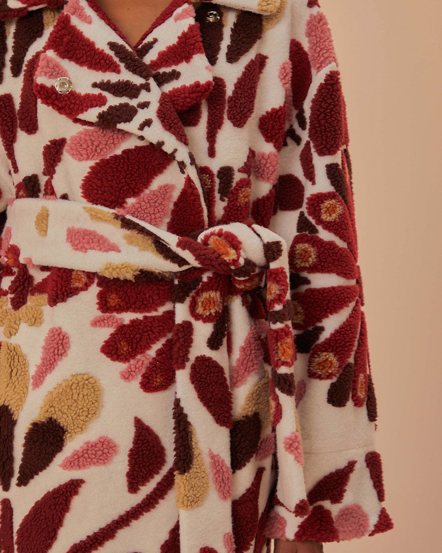 up close of tie waist of fleece midi length coat with red and gold abstract floral print