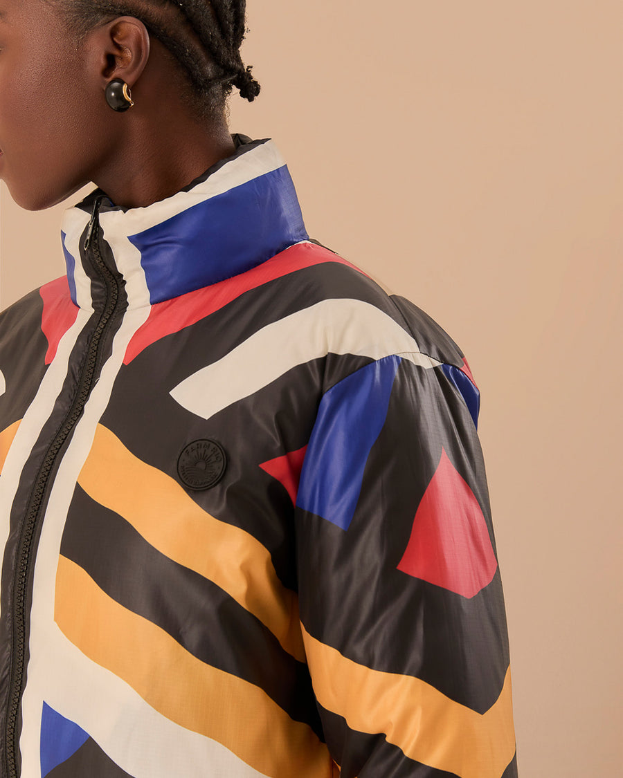 up close of model wearing reversible puffer jacket with colorful geometric stripes