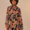 model wearing black short raincoat with colorful abstract bananas print and hood