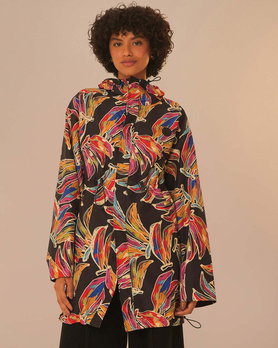 model wearing black short raincoat with colorful abstract bananas print and hood