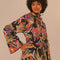 side view of model wearing black short raincoat with colorful abstract bananas print and hood