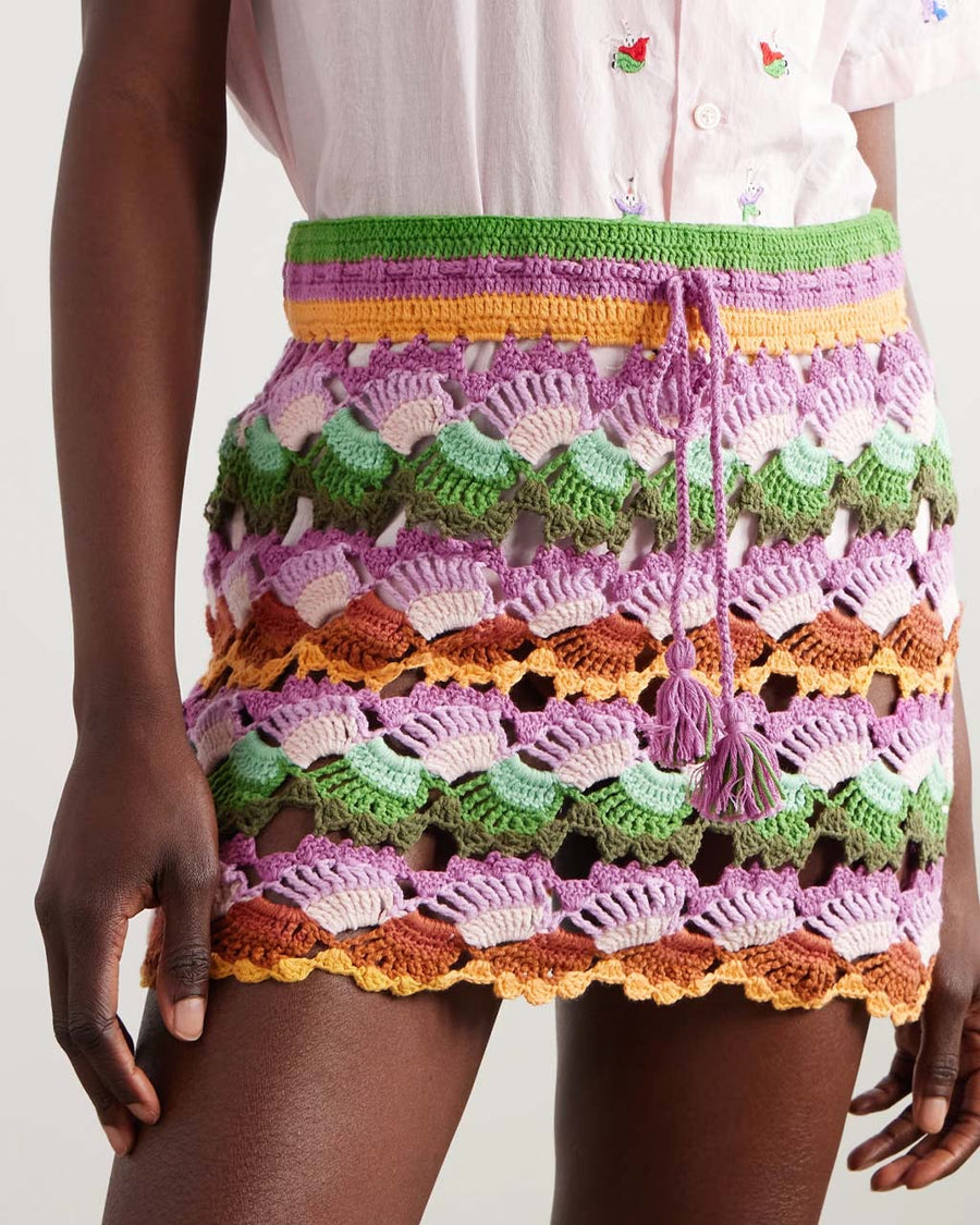 model wearing colorful crochet skirt with crochet tie and scalloped hem