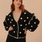 model wearing black cardigan with 3D white floral print, and ruffles on the the sleeves