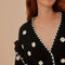 up close of model wearing black cardigan with 3D white floral print, and ruffles on the the sleeves