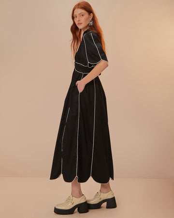 model wearing black cotton midi dress with scallop hem and white piping