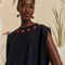 model wearing black cap sleeve top with red beaded heart shapes around the neckline