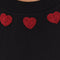 up close of model wearing black cap sleeve top with red beaded heart shapes around the neckline