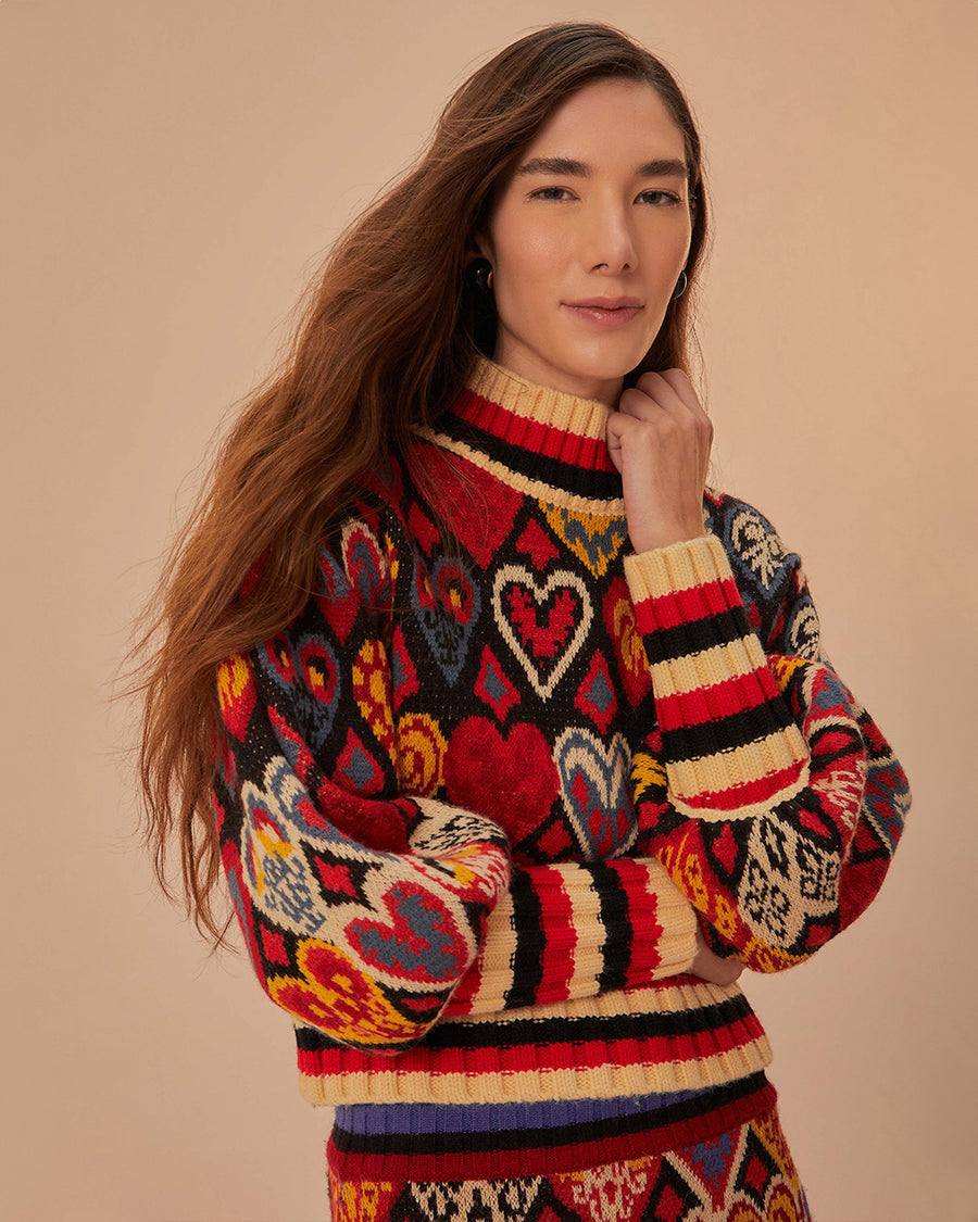 up close of model black sweater with colorful abstract hearts and striped mock neck, sleeve cuffs and hem