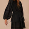 side view of model wearing black long sleeves mini dress with crocheted detail and tie waist