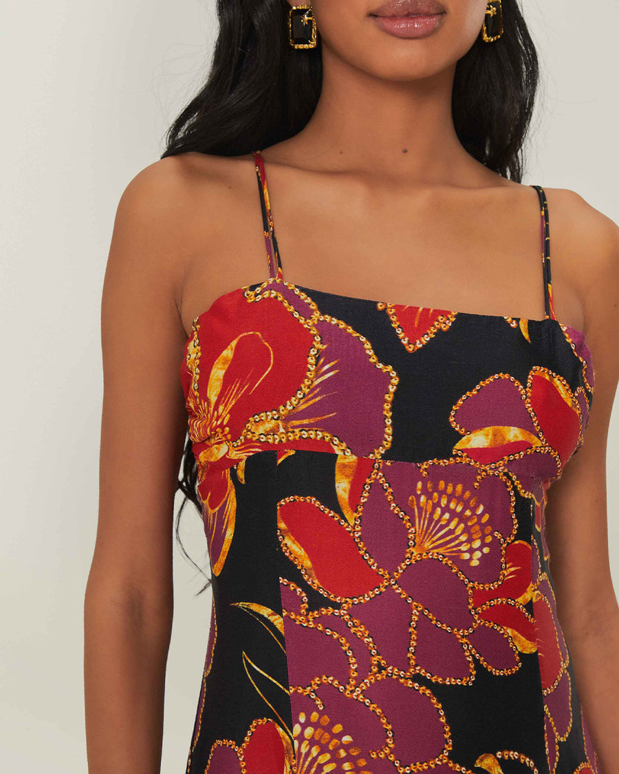 up close of model wearing black tank maxi dress with red and purple flowers with gold accents