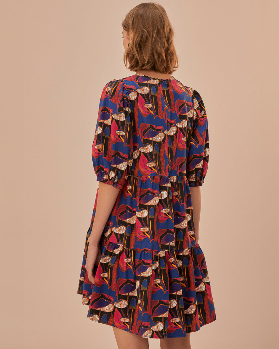 back view of model wearing black mini dress with blue, red and cream wild mushroom print and puff short sleeves