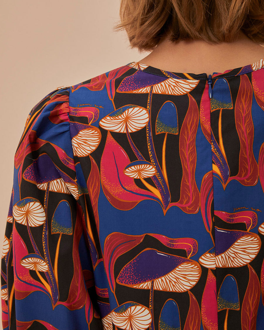 up close of model wearing black mini dress with blue, red and cream wild mushroom print and puff short sleeves