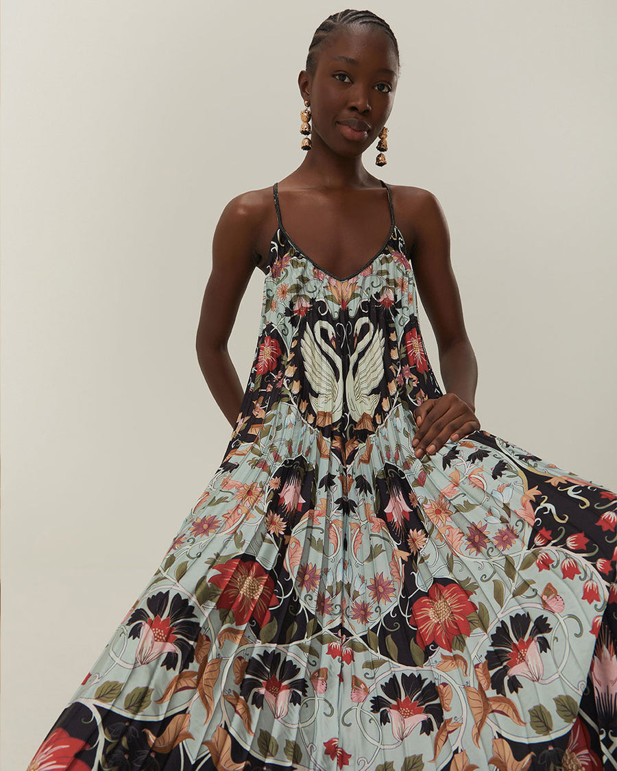 up close of model wearing light blue and black pleated midi dress with floral and swan design