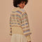 back view of model wearing cream cropped cardigan with puff sleeves with colorful woven stripe pattern