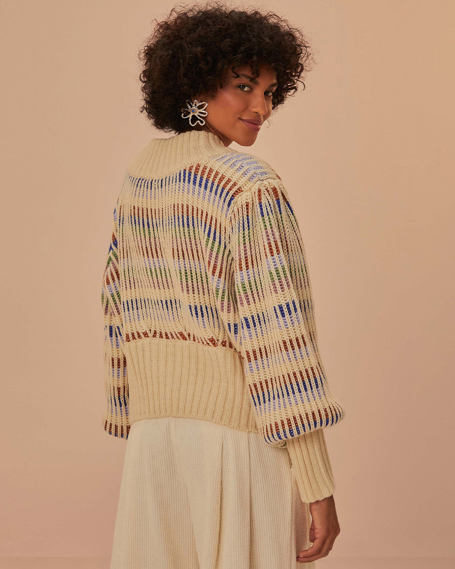 back view of model wearing cream cropped cardigan with puff sleeves with colorful woven stripe pattern