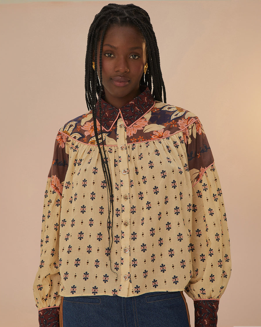 model wearing cream button down blouse with button sleeves, collar, and colorful floral trim