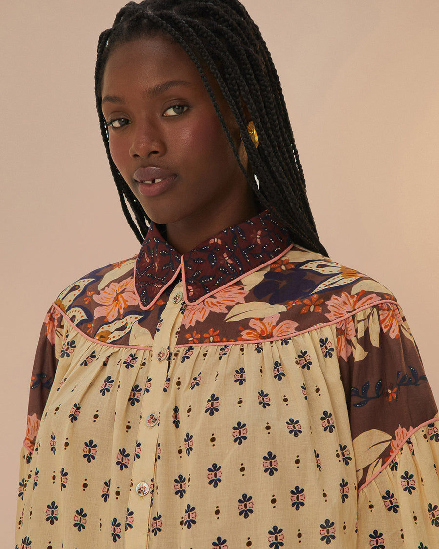 up close of model wearing cream button down blouse with button sleeves, collar, and colorful floral trim