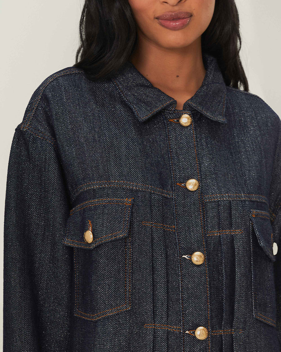 up close of model wearing shimmery blue denim jacket with button front and patch front pockets