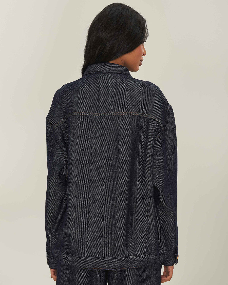 back view of model wearing shimmery blue denim jacket with button front and patch front pockets