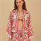 model wearing cropped white and red stripe button down top with flared sleeves and floral and chain charm print