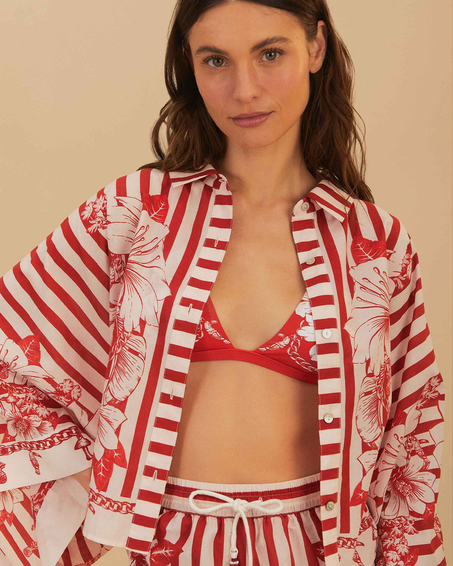 up close of model wearing cropped white and red stripe button down top with flared sleeves and floral and chain charm print