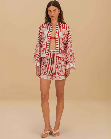 model wearing white and red stripe shorts with beaded tie waist tassels, dolphin hem sides and floral and chain charm print