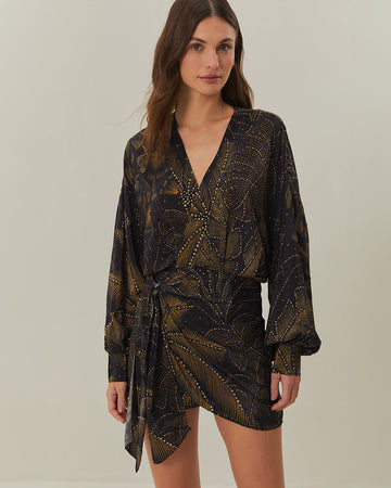 model wearing black mini dress with tie waist, long sleeves and golden foliage print