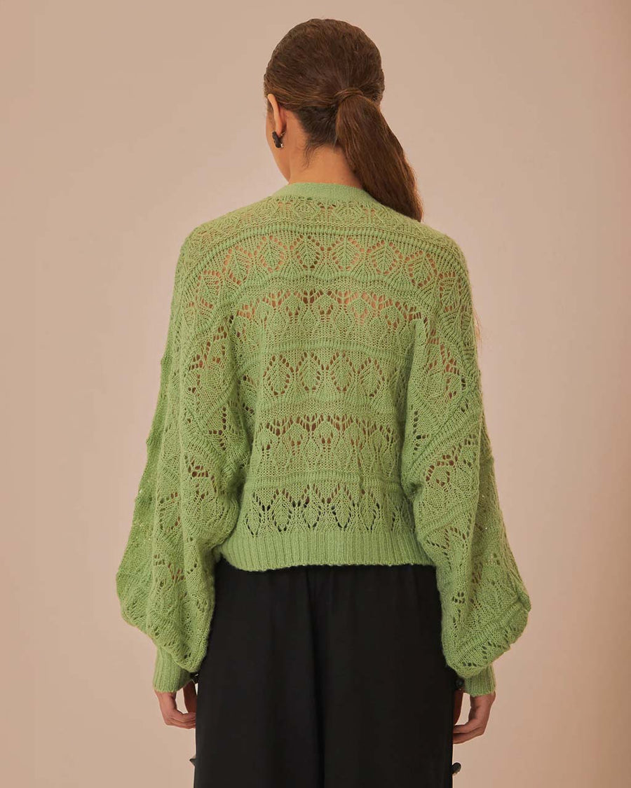 backview of model wearing light green textured open knit cardigan